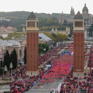 Miles de corredoras en la salida de la Carrera de la Mujer de Barcelona junto a las torres venecianas